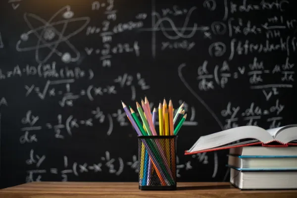 Back to school supplies. Books and blackboard on wooden background,education